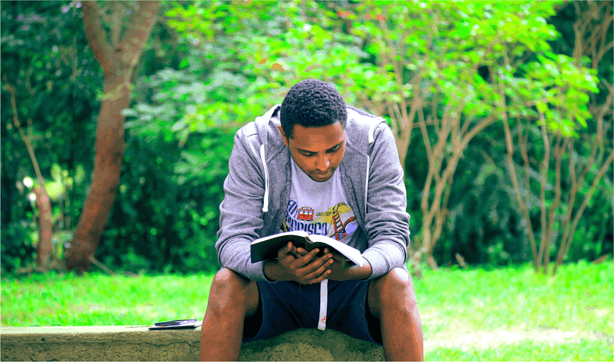 man reading book in a park 